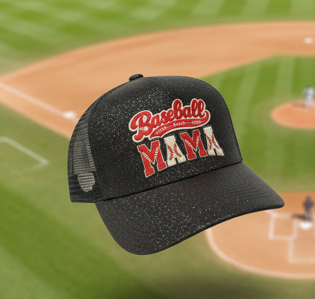 Two baseball caps with 'Baseball MAMA' DTF print are shown floating over a blurred baseball field background. One cap is black with a glittery finish, and the other is white and red with a mesh back.