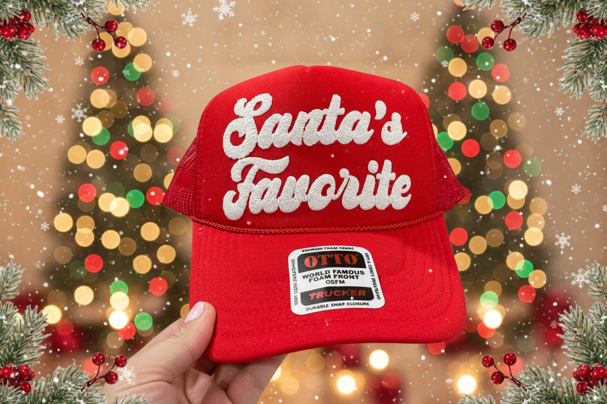 A red trucker hat with 'Santa's Favorite' written in white puff glitter vinyl on the front.