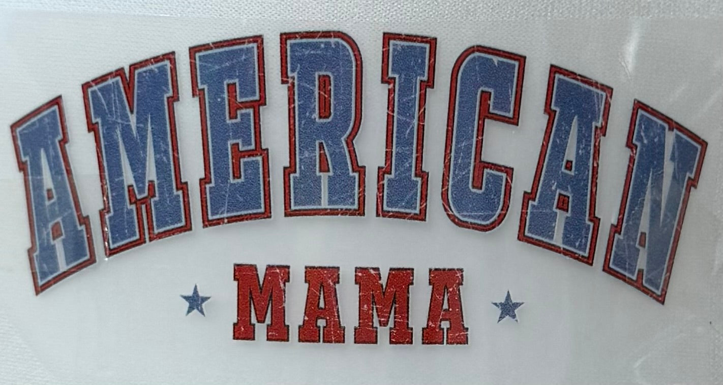 A close-up of a distressed collegiate-style graphic reading 'AMERICAN MAMA' on a white background, with blue letters outlined in red and red 'MAMA' text with small blue stars.