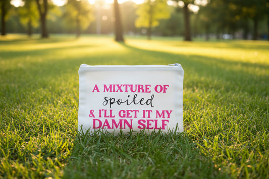 A white canvas zipper bag with black and pink text that reads: 'A MIXTURE OF spoiled & I'LL GET IT MY DAMN SELF'.