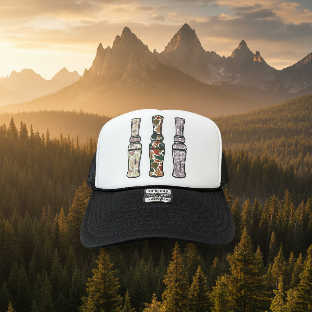 A black and white trucker hat with a camouflage pattern on the front panels, resting on a rustic wooden surface.