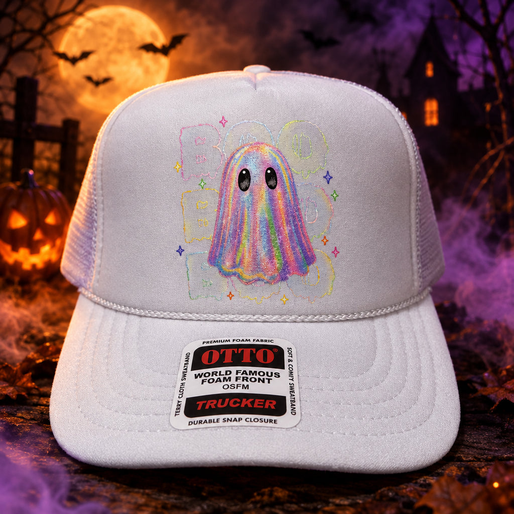 A white trucker hat with a colorful ghost graphic on the front panel and a visible Otto Trucker sticker on the brim, displayed on a wooden surface.