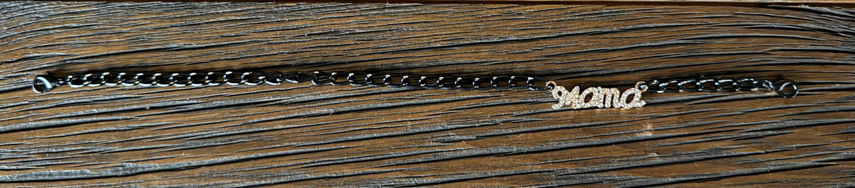 A dark metal hat chain with a custom script nameplate spelling 'Mama' in a light gold tone, displayed on a dark wood background.
