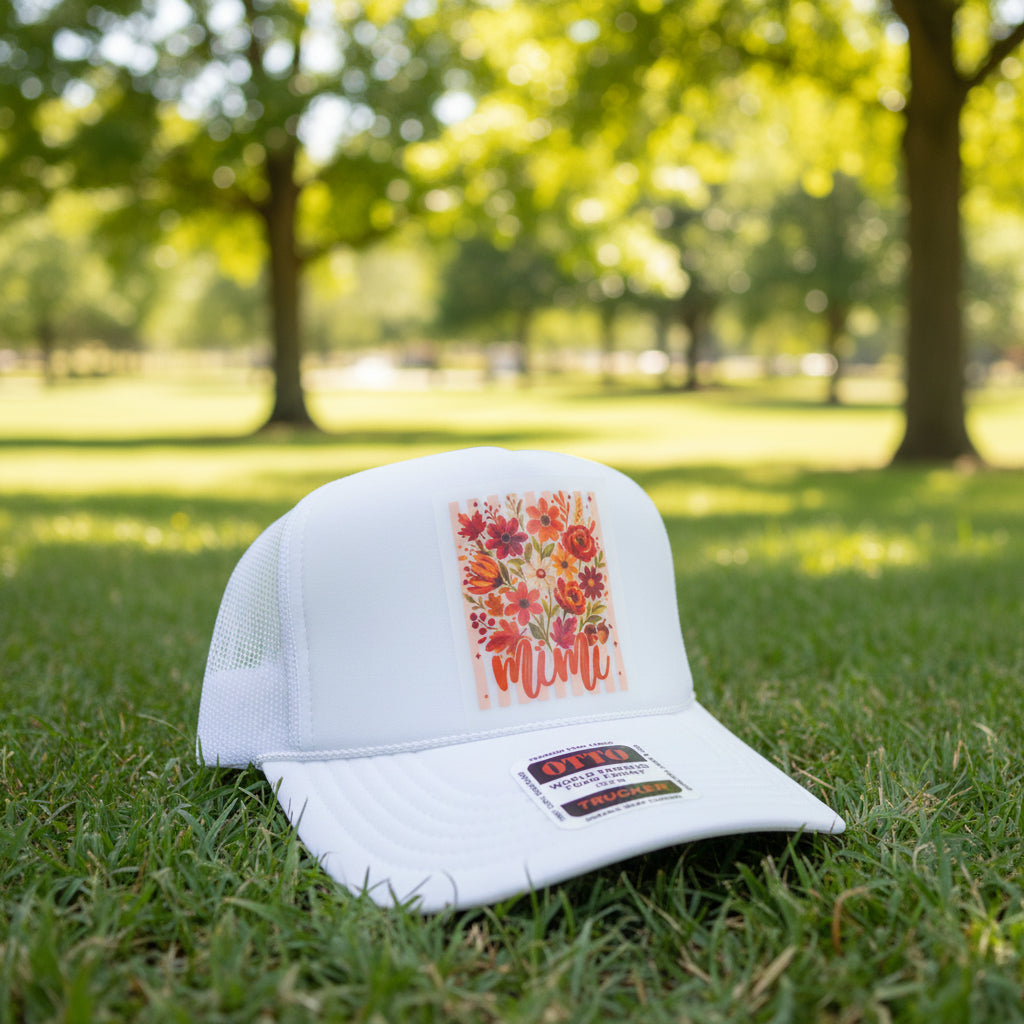 A white trucker hat with a floral patch on the front and an OTTO brand sticker on the brim, displayed on a wooden surface.
