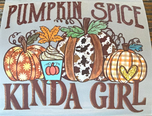 A square white sticker or decal with a fall-themed illustration and the text 'PUMPKIN SPICE KINDA GIRL' in brown lettering, placed on a wooden surface.