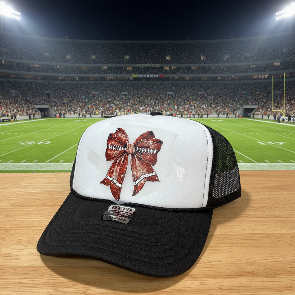 A black and white trucker hat with a distressed brown and white bow graphic on the front panel.
