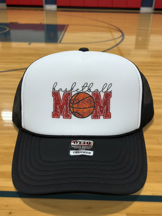 A white and black trucker hat with a 'basketball MOM' graphic on the front.