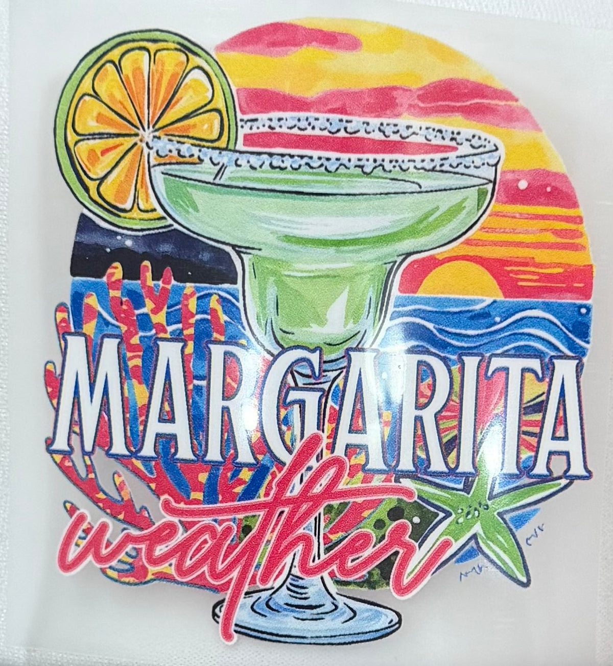 A colorful printed design featuring a margarita glass with a lime wheel, a sunset background, waves, coral, and the words “MARGARITA weather” in large stylized lettering.