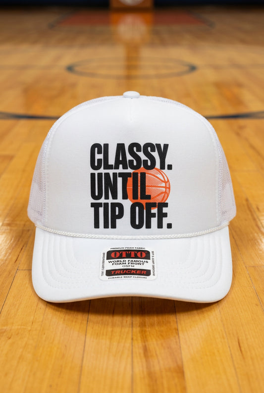 A white trucker hat with a white foam front panel and black mesh side/back panels, featuring the text 'CLASSY. UNTIL TIP OFF.