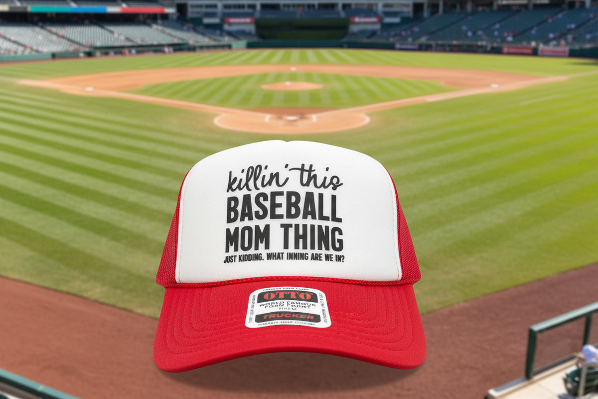 A red and white trucker hat with a foam front panel featuring the text 'killin' this BASEBALL MOM THING' and a visible Otto brand sticker on the brim.