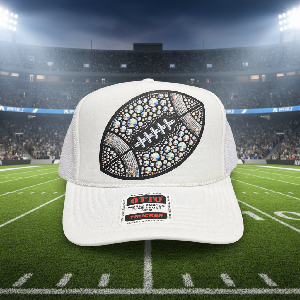 A white trucker hat with a foam front panel, featuring a large decorative football graphic embellished with iridescent rhinestones and laces. The brim has a visible Otto Trucker label.