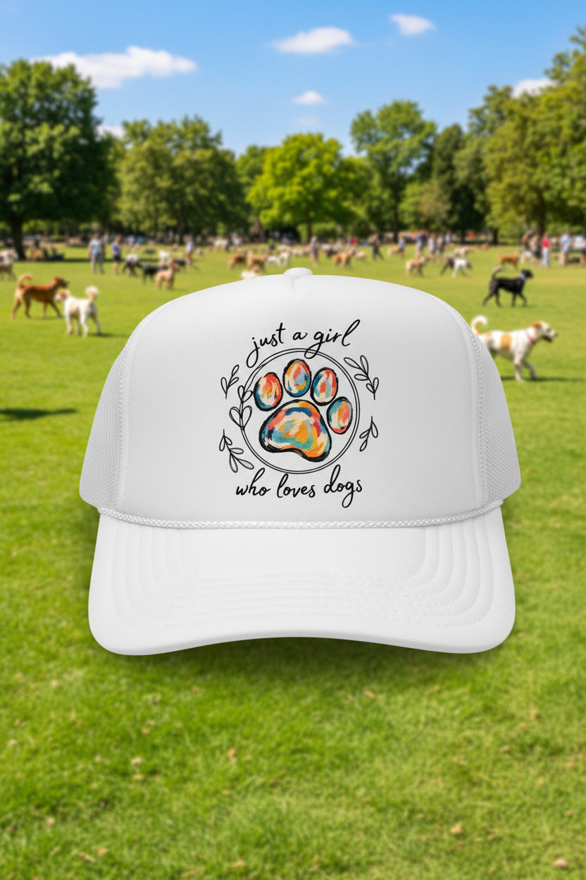 A white trucker hat with a colorful dog paw print graphic and the text 'just a girl who loves dogs' on the front.
