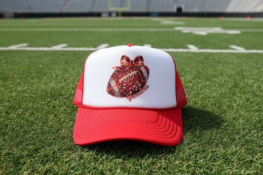 A red and white trucker hat featuring a glittery football graphic with a red bow and the text 'Grandma' on the front panel. The brim has a visible 'OTTO' foam fabric sticker.