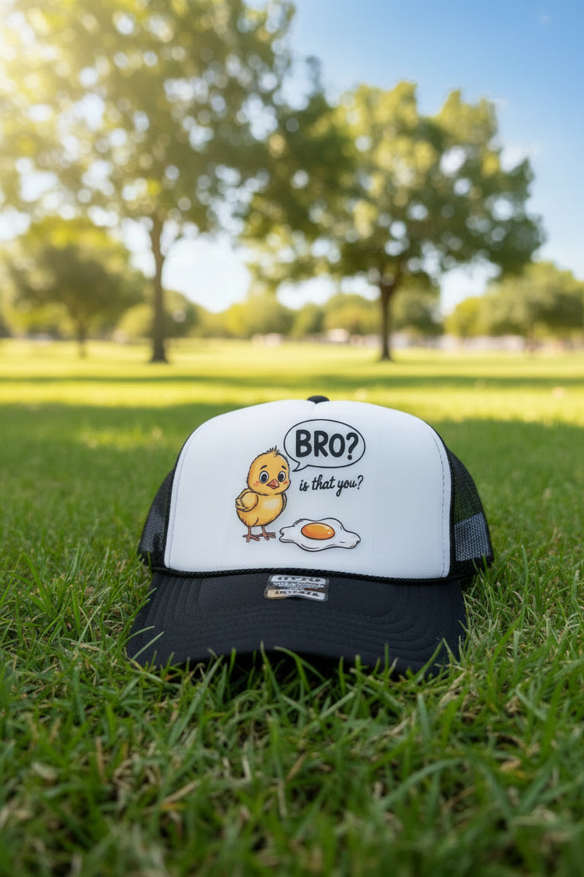A black and white trucker hat with a cartoon yellow chick and a fried egg graphic on the front, with a speech bubble that says 'BRO? is that you?'.