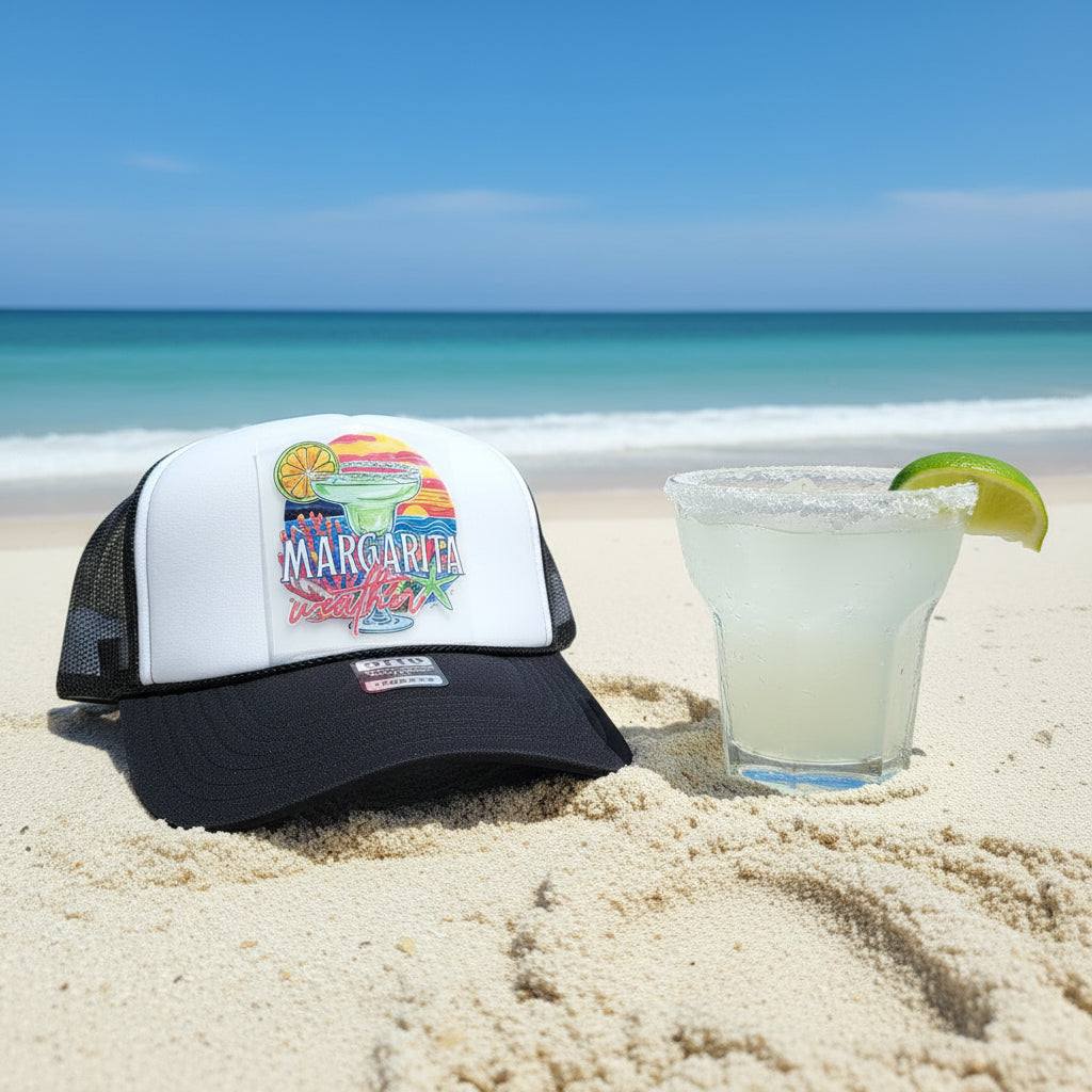 A black and white trucker hat with a colorful 'Margarita Weather' graphic on the front panel.