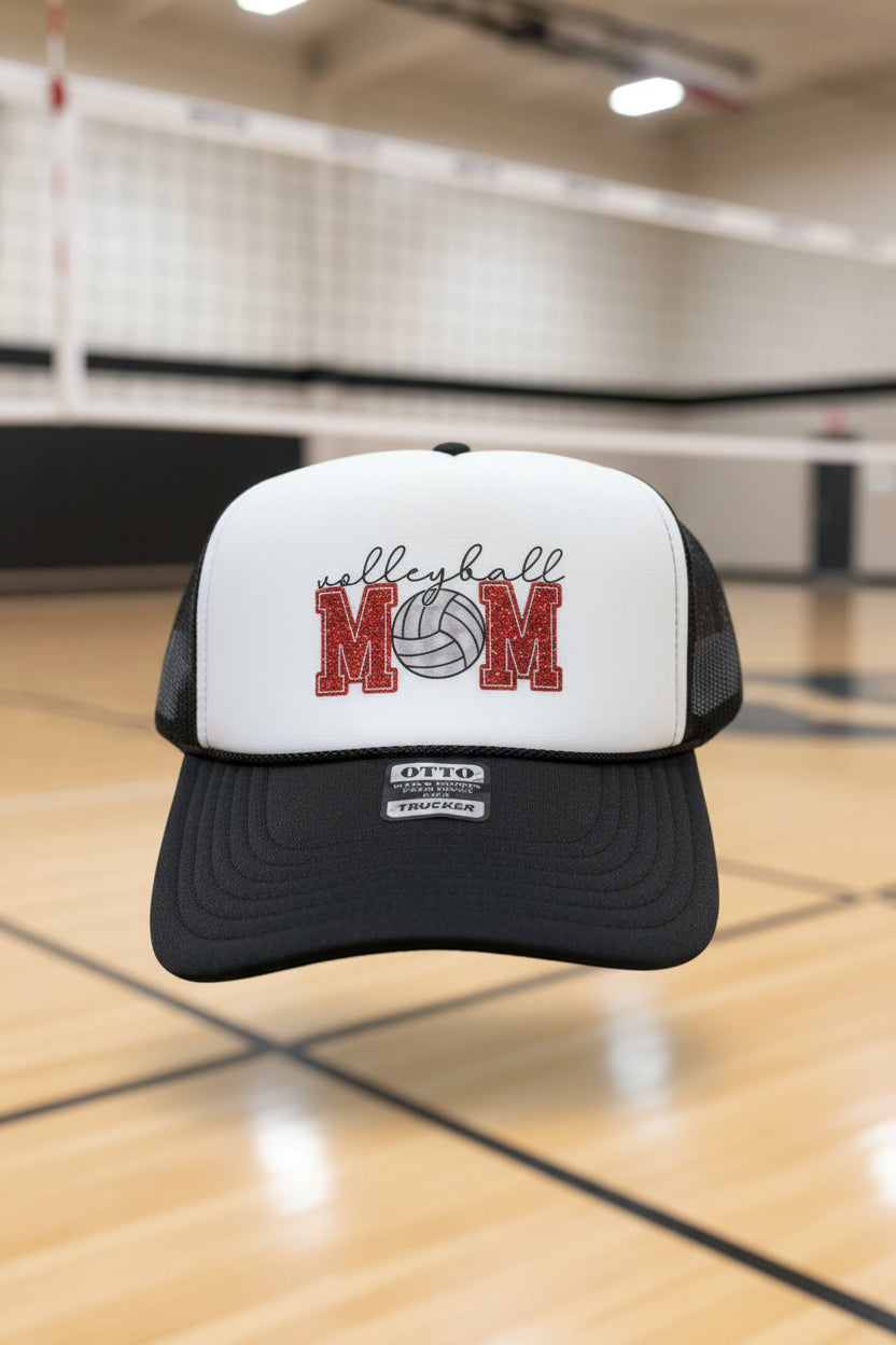 A black and white trucker hat with a custom 'MOM Volleyball' graphic on the front panel.
