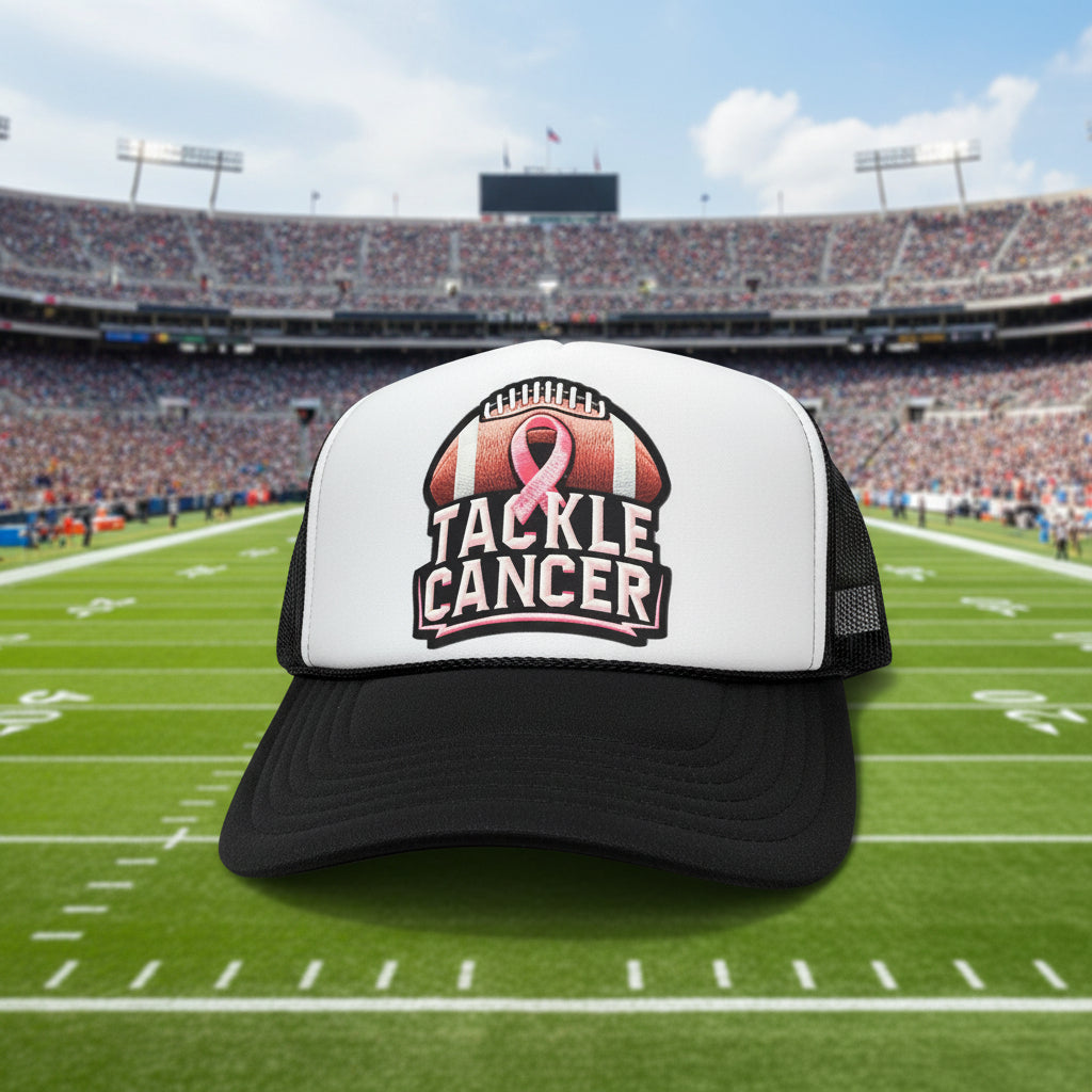 A black and white trucker hat featuring a front patch that reads 'TACKLE CANCER' with a pink ribbon & football graphic.