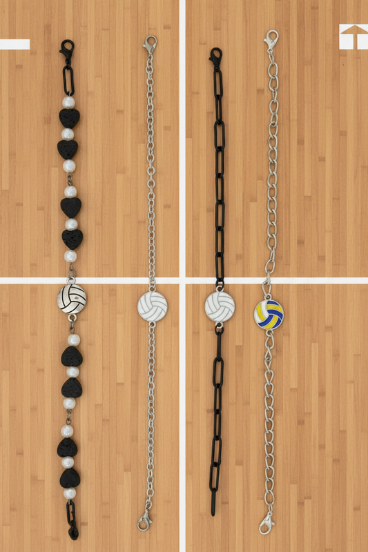 Four beaded and chain bracelets laid flat on a dark wood background. Three bracelets feature black and white beads with silver-toned links, and one bracelet features a yellow and blue volleyball charm on a silver chain.