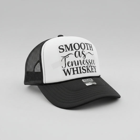 A black and white trucker hat with the phrase 'SMOOTH as Tennessee WHISKEY' printed on the front panel. The hat has a black brim, black mesh back, and a silver-tone metal badge on the front of the brim that reads 'OTTO WORLD FAME TRUCKER'.