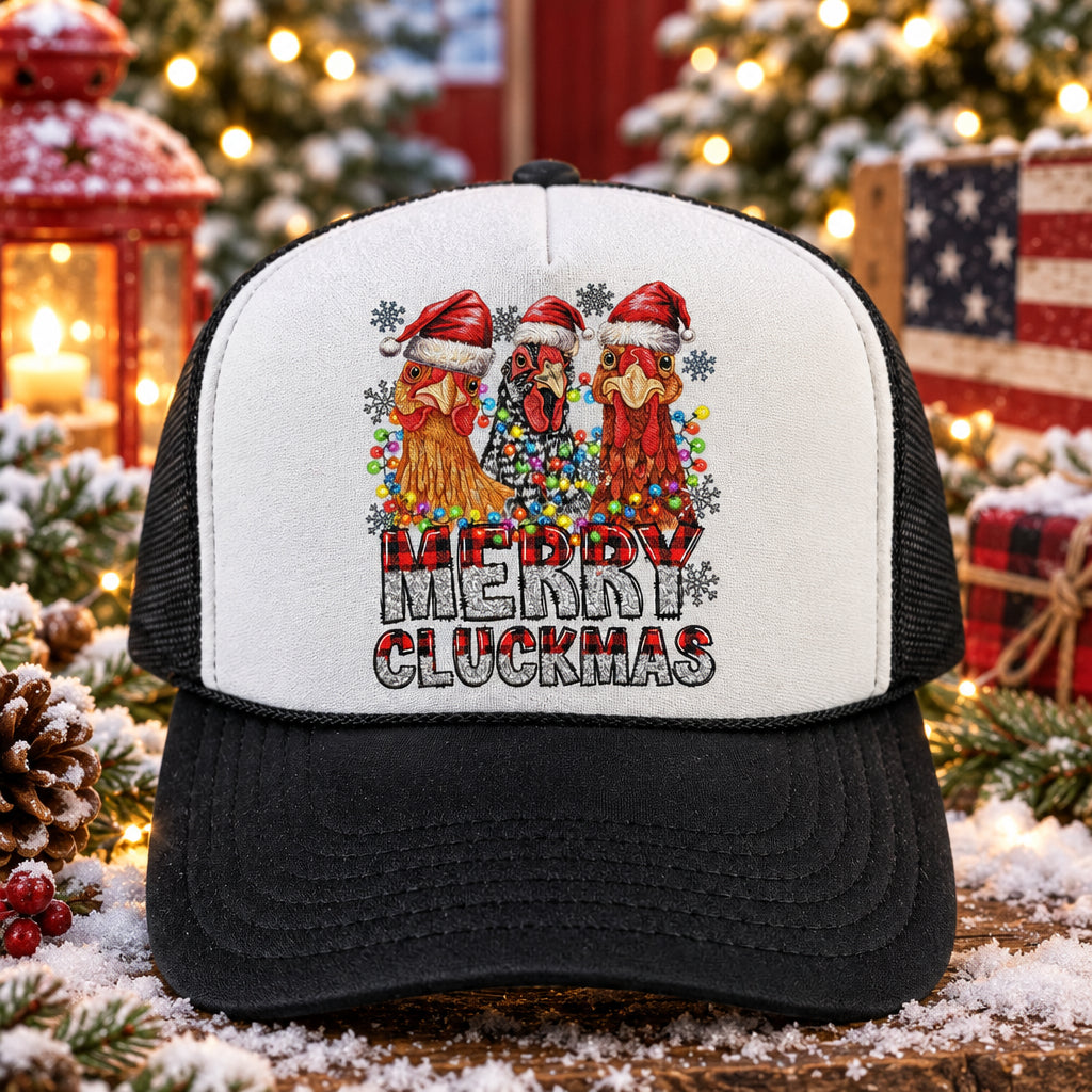 A black and white trucker hat with a 'Merry Cluckmas' graphic on the front, resting on a wooden surface.