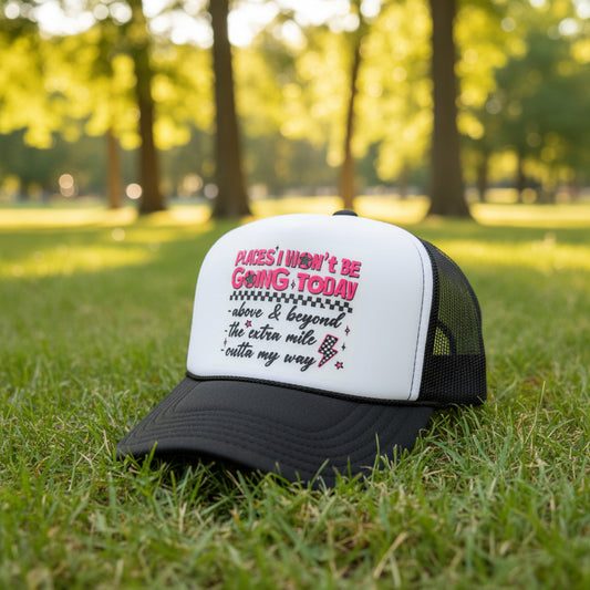 A dark gray and white trucker hat with a graphic text print on the front, displayed on a dark wooden table against a wood-paneled background.