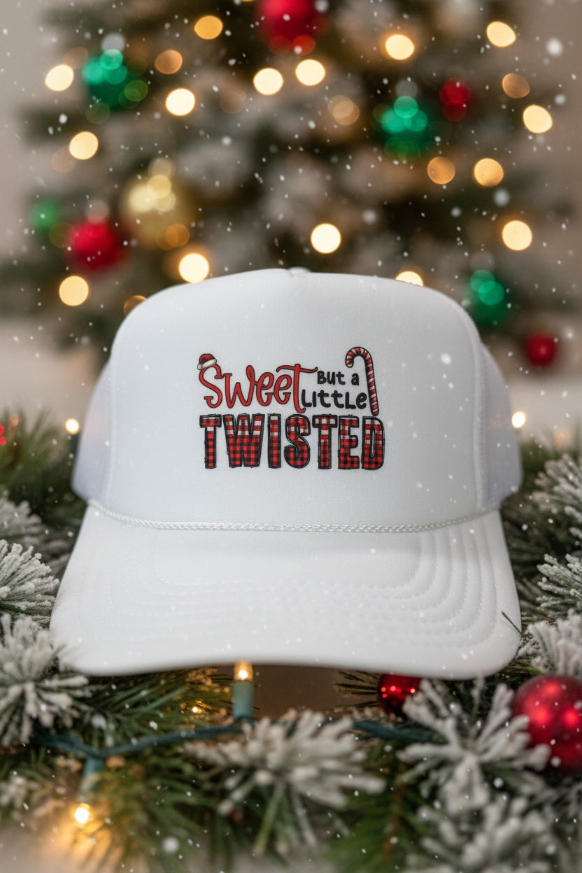 A white trucker-style cap with a design reading 'Sweet but a little TWISTED' in red and black plaid lettering